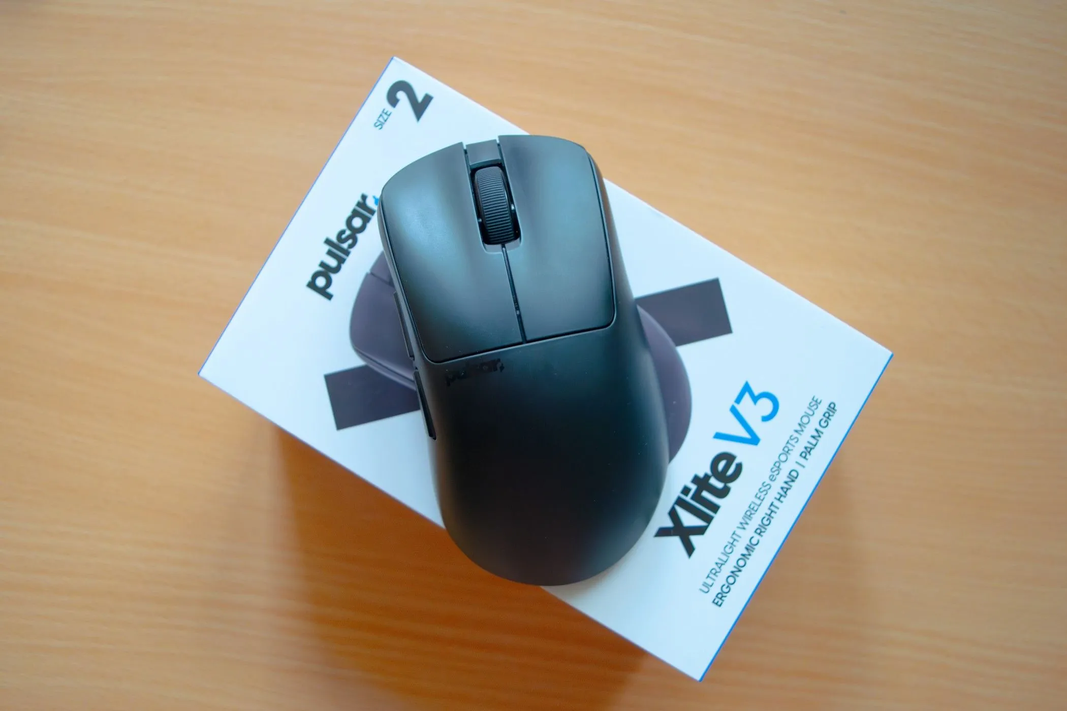 Chuột gaming Pulsar Xlite V3 đặt trên hộp sản phẩm, minh họa thiết kế tổng thể và nút bấm có tiếng click to.