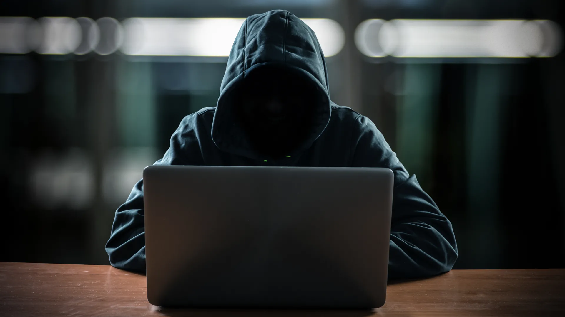 Hình ảnh một hacker ngồi trước màn hình máy tính trong bóng tối, tượng trưng cho mối đe dọa an ninh mạng và các cuộc tấn công dữ liệu qua cổng kết nối điện thoại.