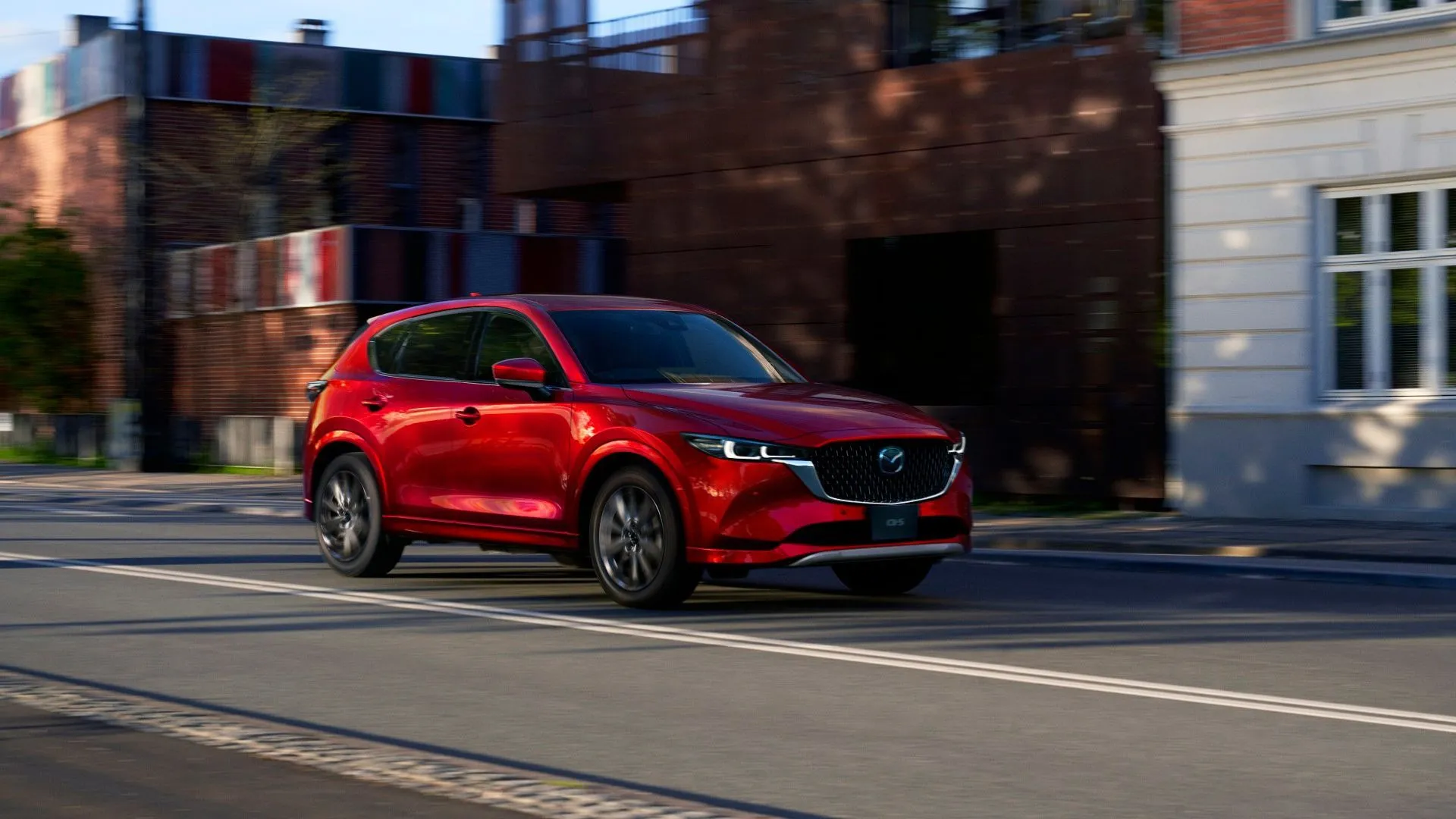 Mặt trước xe Mazda CX-5 đời mới màu đỏ đang đỗ, với thiết kế đèn pha và lưới tản nhiệt hiện đại.