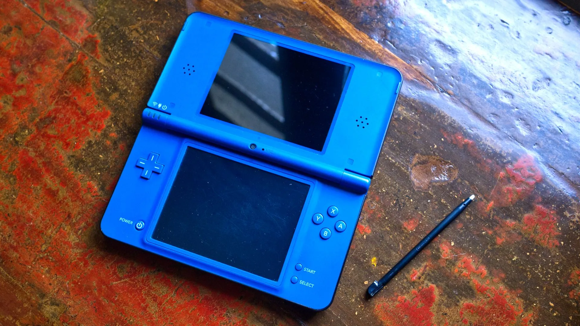 Máy Nintendo DSi XL màu xanh đang mở cùng với bút stylus