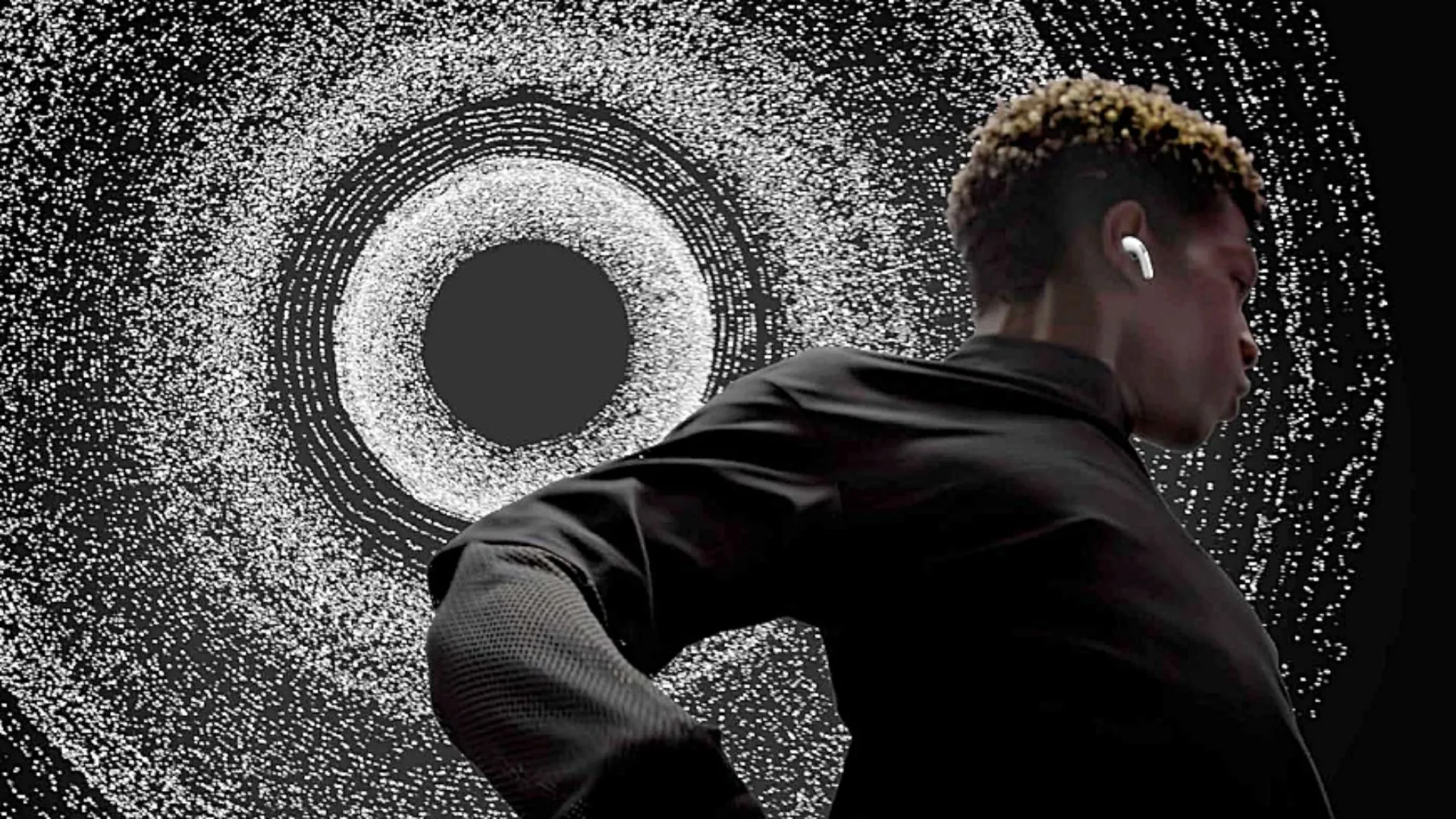 Một người đàn ông đeo tai nghe Apple AirPods Pro (Thế hệ thứ 2) với ánh sáng đẹp mắt ở phía sau.