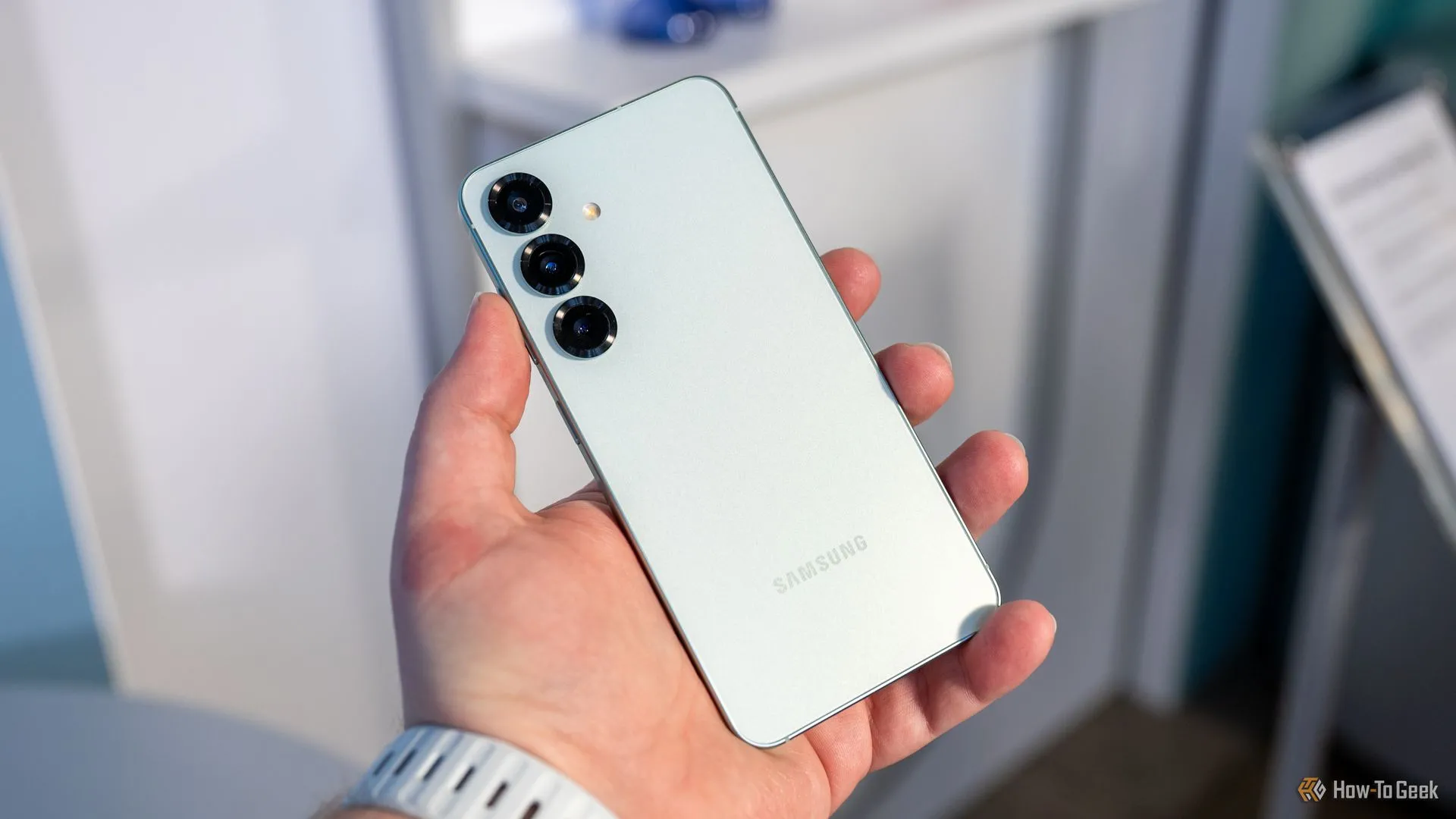 Một người dùng đang cầm Samsung Galaxy S25 và nhìn vào cụm camera sau của điện thoại.