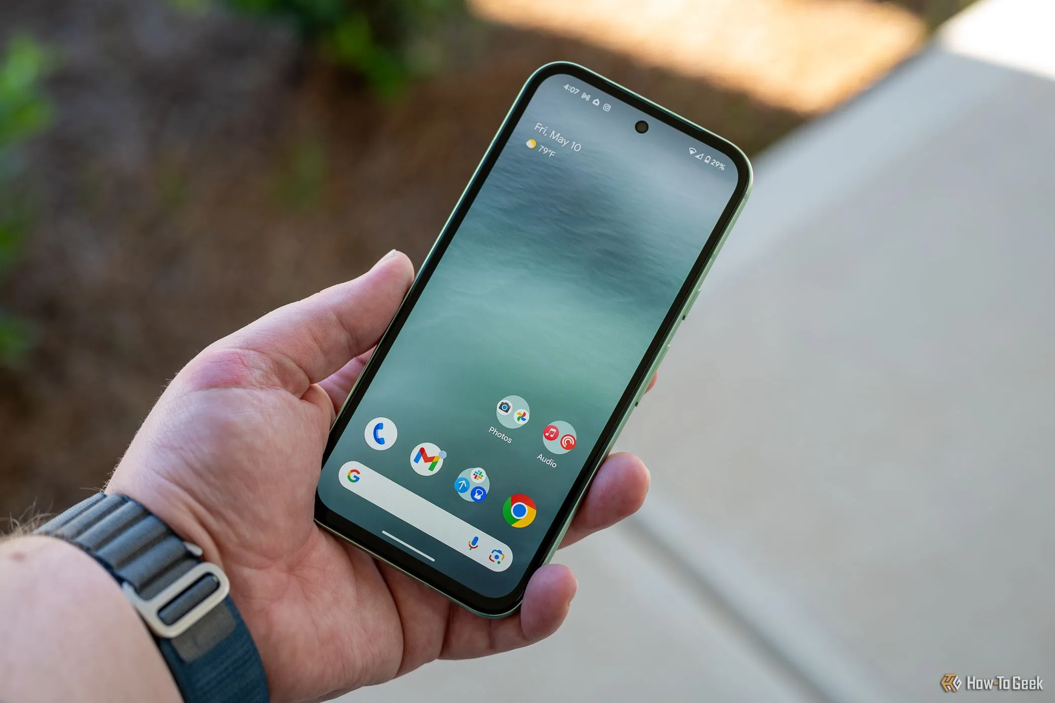 Người dùng cầm Google Pixel 8a hiển thị màn hình chính và viền máy