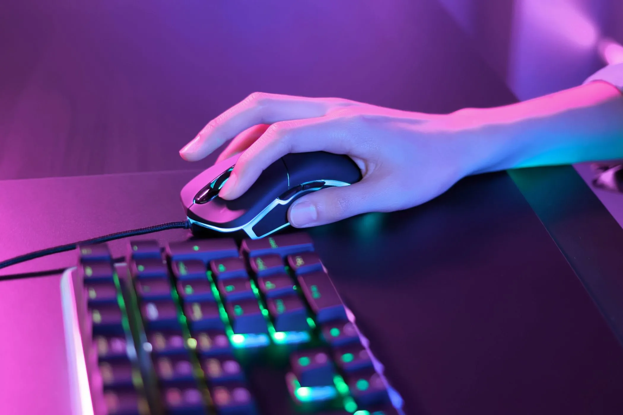 Người dùng đang sử dụng chuột gaming và bàn phím RGB dưới ánh đèn neon