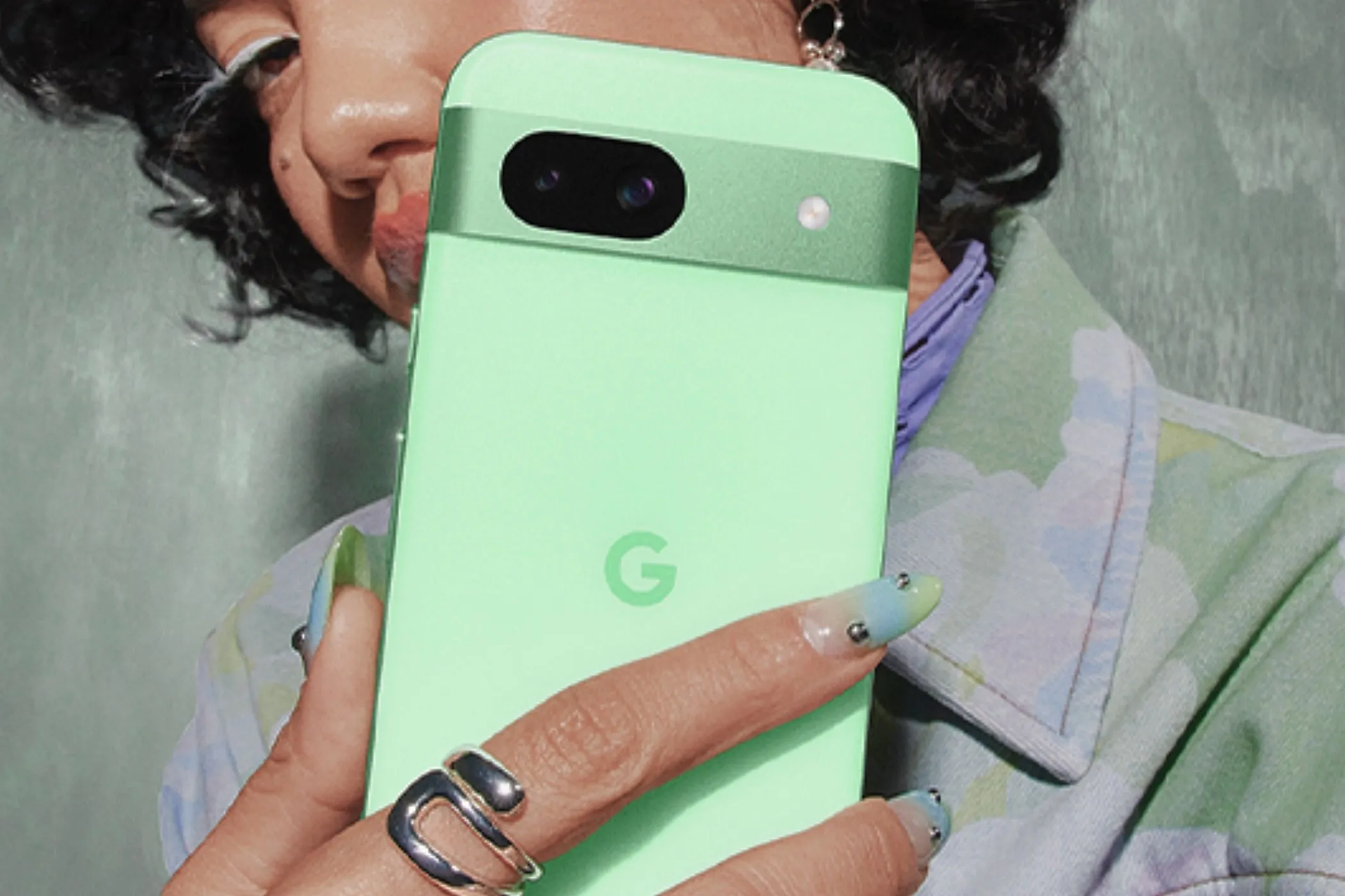 Người phụ nữ cầm điện thoại Google Pixel 8a màu xanh Aloe thanh lịch.