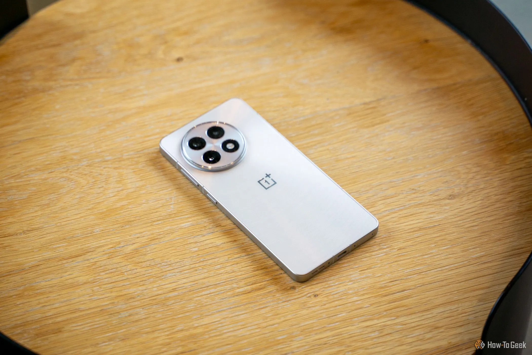 OnePlus 13R đặt úp mặt trên bàn gỗ hiển thị cụm camera