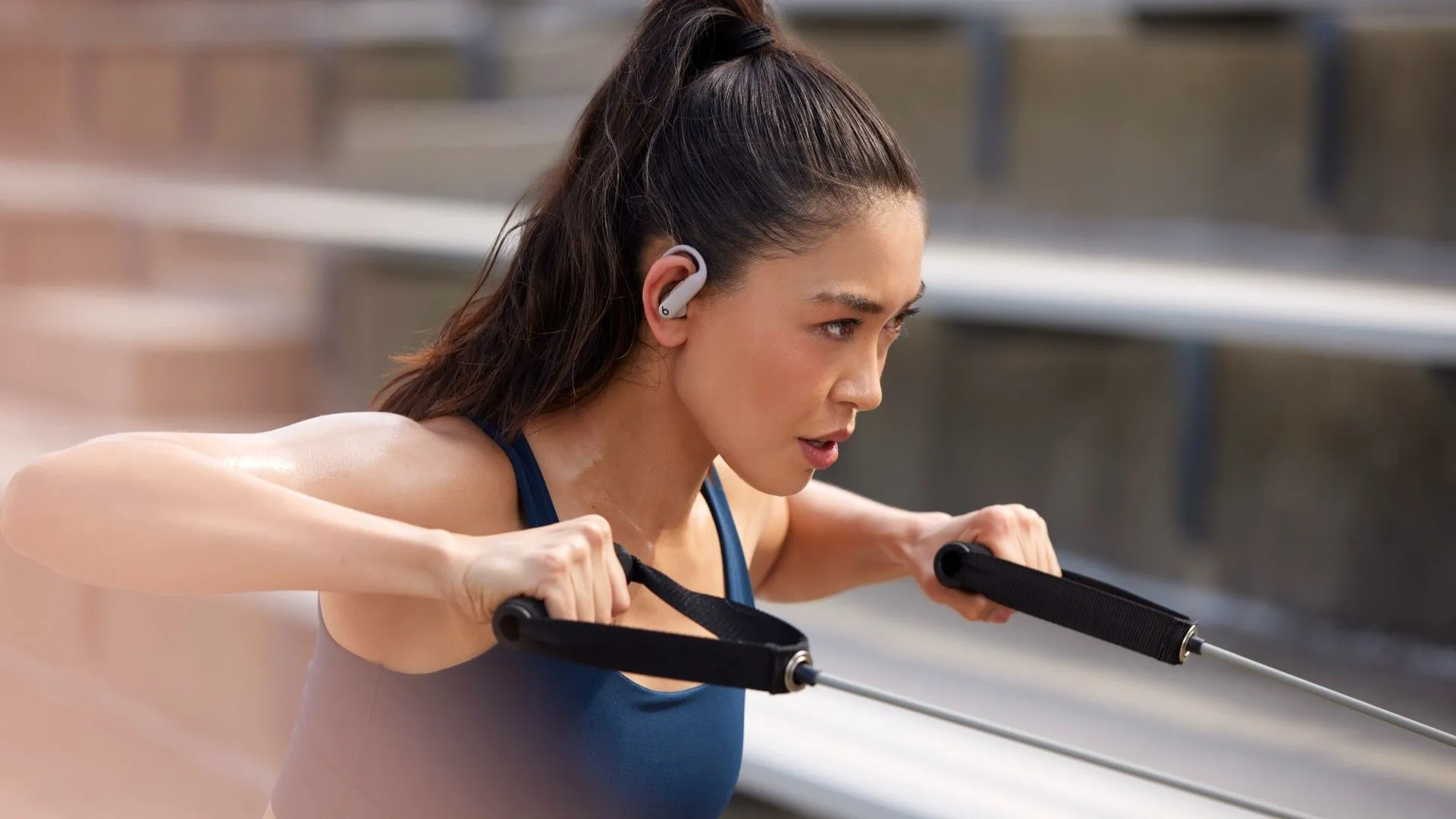 Tai nghe Powerbeats Pro 2 màu đen đeo trên tai một người phụ nữ đang tập thể dục