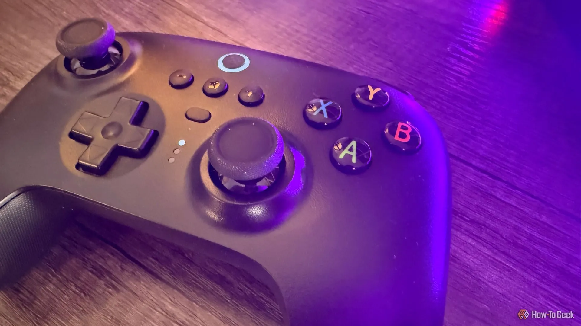 Tay cầm 8BitDo Ultimate 2.4G với cần gạt Hall Effect, đặt trên bàn có ánh sáng tím.